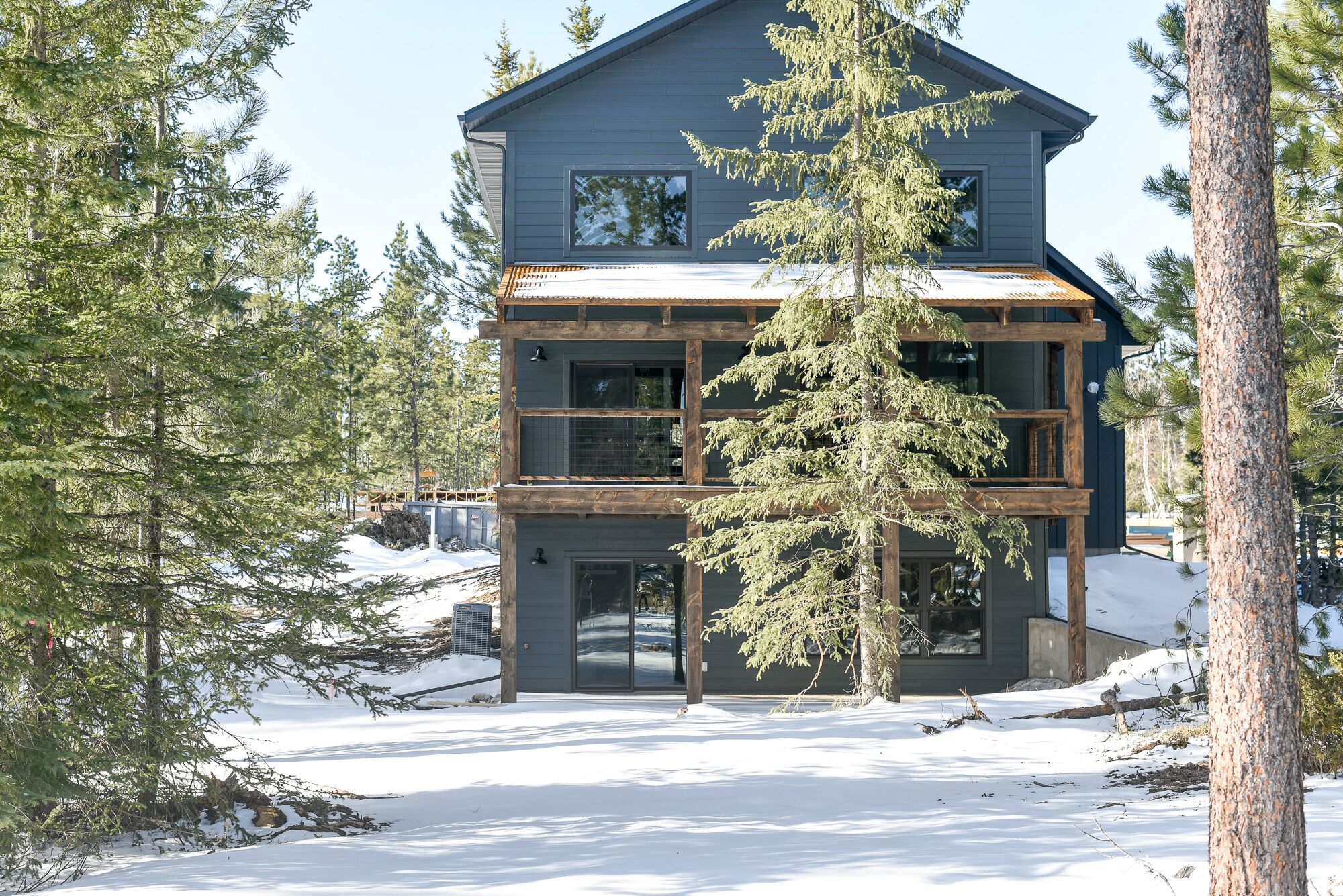 Un bâtiment à deux étages, à l’extérieur sombre, doté de grandes fenêtres et d’une terrasse en bois.