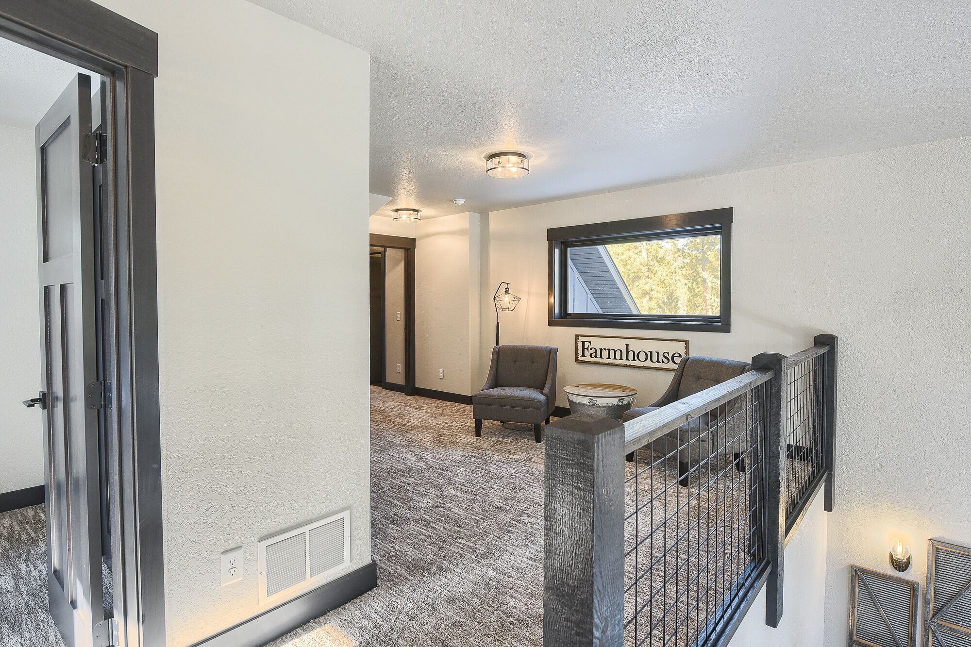 A hallway with a staircase, a chair, a table, and a sign that reads 'Farmhouse.'