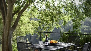 An outdoor dining area with a table set for two, surrounded by chairs, a bottle of wine, and a plate of fruit. - Villa Dol (Postira)