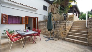 An outdoor patio with a table and chairs, a staircase, and a covered area with a green umbrella. - Orchid Spadici / Apartment Orchid Spadici (Porec)