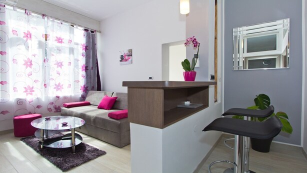 A modern living room with a sofa, a glass coffee table, a small round table, and a chair. - Orchid Spadici / Apartment Orchid Spadici (Porec)