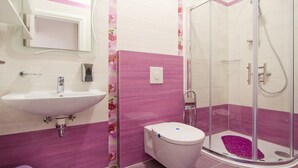 A bathroom with a white sink, a toilet, and a glass-enclosed shower area. - Orchid Spadici / Apartment Orchid Spadici (Porec)