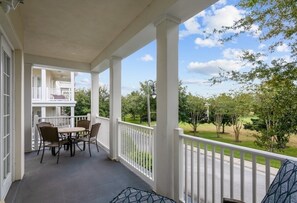 Relax on the covered porch with a table and four chairs, surrounded by lush greenery and a serene view.