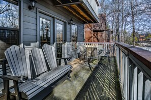 A wooden deck with Adirondack chairs, a table, and a railing. - Hey Diddle Diddle 3 Bedroom Cabin by RedAwning (Pigeon Forge)