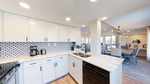 A modern kitchen with white cabinets, a patterned backsplash, and a central island. - Completely Updated Two Bedroom Condominium with Sweeping Marina Views! (Hilton Head)