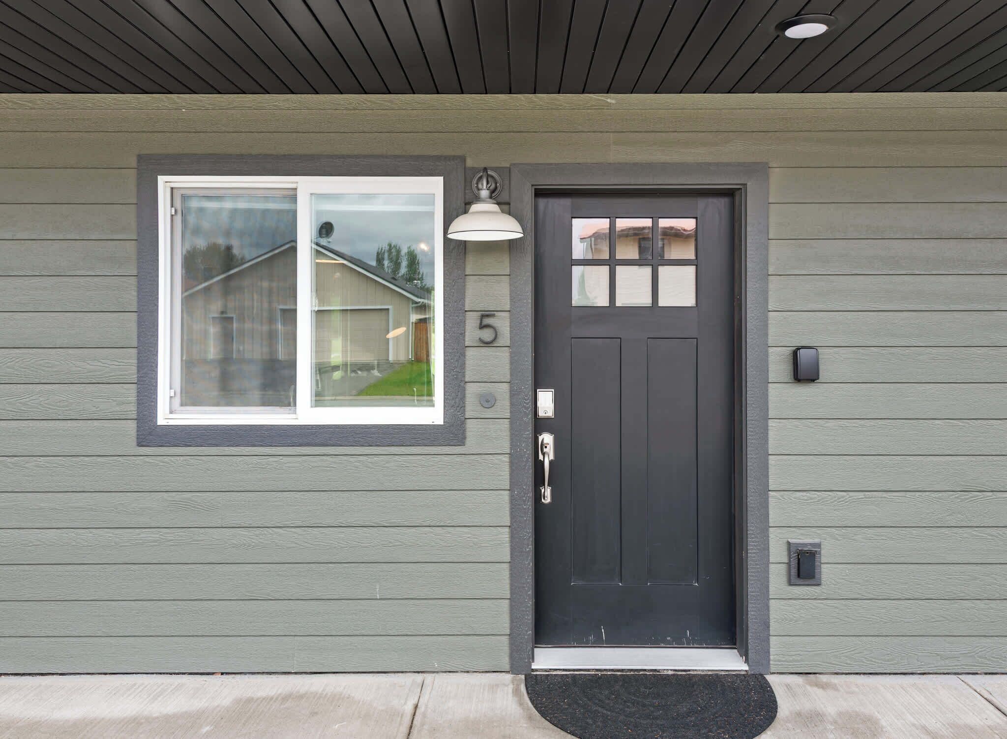 A house with a dark front door, a mailbox, and a window with a view of a garage.