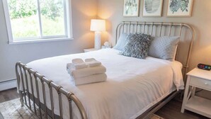 A neatly made bed with folded towels, a bedside lamp, and a nightstand with a remote control.