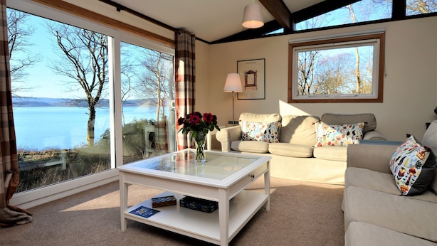 Un salon avec une table basse en verre, un canapé et une vue sur un lac.