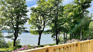 Une terrasse en bois offrant une vue sur un lac et des arbres.