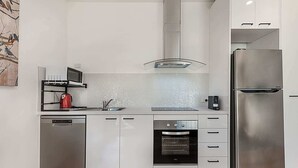A modern kitchen with a stainless steel refrigerator, an oven, a microwave, and a dishwasher. - Comfy Studio with Shared Backyard near Racecourse (Carnegie)