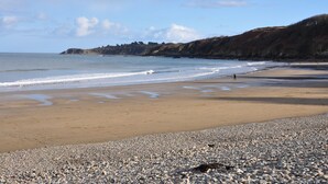 A pebbly beach with a rocky shoreline and a distant view of a hill. - La Maison d'Anne-Marie, charming vacation rental (Saint-Clet)