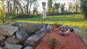 A garden with red gravel, rocks, and a wooden fence. - La Maison d'Anne-Marie, charming vacation rental (Saint-Clet)