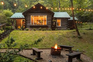 Eine Blockhütte mit Feuerstelle und Bänken im Garten.