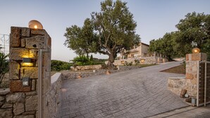 A stone pathway leading to a stone gate with a tree in the center. - Arca Villa   Enchanting Sunset! (Keri)