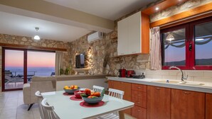 A modern kitchen with a stone wall, wooden cabinets, and a view of the sea. - Arca Villa   Enchanting Sunset! (Keri)
