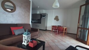 A living room with a sofa, a coffee table, and a dining area with a table and chairs. - Casa Maffei TOP apartment 3, 2nd floor, balcony, fantastic lake view, parking (Tignale)