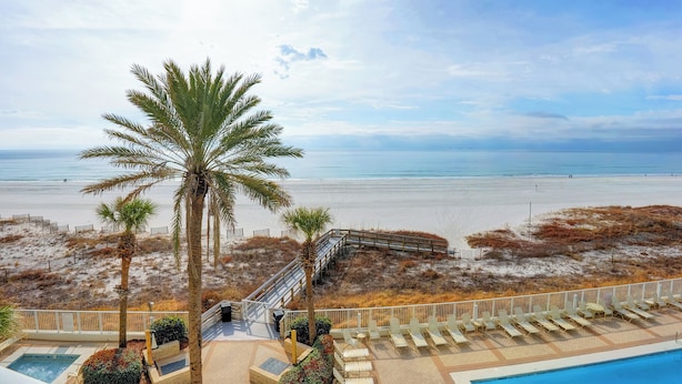 Une vue sur la plage, avec des palmiers, une piscine et une terrasse en bois.