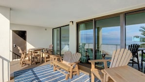 Un balcon doté de mobilier en bois, comprenant des chaises et une table, et offrant une vue sur l’océan.
