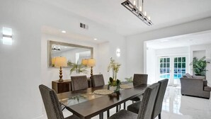 A modern dining area with a rectangular table, six upholstered chairs, two floor lamps, and a large mirror above the table. - Luxe Mansion/10min Walk Beach/Gameroom/Heated pool (Hollywood)