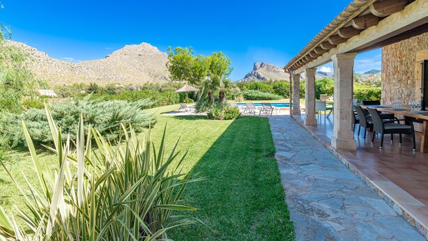 A patio area with stone flooring, a pool, and a dining setup.