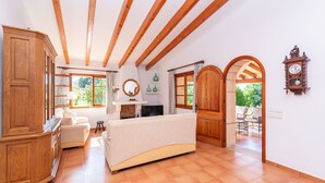 A spacious living room with a fireplace, wooden beams, and a view of the outdoors.