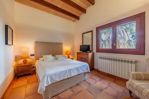 Relax in this serene bedroom with a large bed, two nightstands, and a dresser, offering a peaceful view of palm trees.