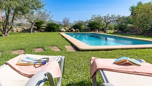 A swimming pool with a grassy area, two lounge chairs, and a book on each. - Villa Marc, 4 bedrooms, private swimming pool, BBQ, Pollensa (Pollensa)