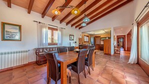 A spacious dining area with a wooden table and chairs, a kitchen in the background, and a high ceiling with exposed beams. - Villa Marc, 4 bedrooms, private swimming pool, BBQ, Pollensa (Pollensa)