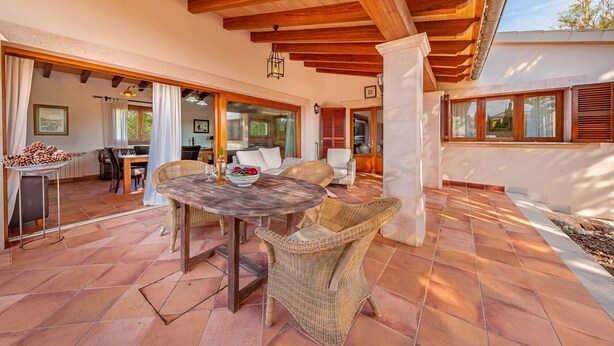 An outdoor patio with a round table and wicker chairs, a wooden ceiling, and a view of the interior through glass doors. - Villa Marc, 4 bedrooms, private swimming pool, BBQ, Pollensa (Pollensa)