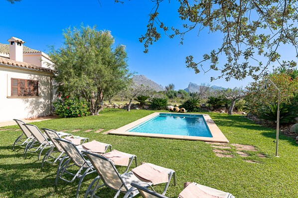 Relax by the serene pool surrounded by lush greenery and a scenic mountain backdrop.