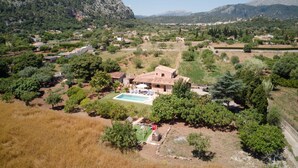 Una villa con piscina rodeada de árboles y montañas al fondo.