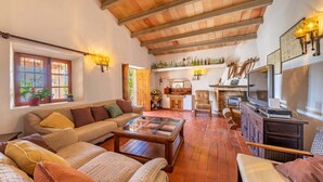 Amplia sala de estar con techo de madera alto, chimenea, televisor y diversas opciones de asientos.