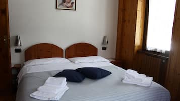 Ein ordentlich bezogenes Bett mit Kissen und einem zusammengeklappten Handtuch, sowie ein Bild an der Wand.
