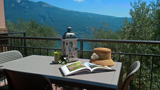 A balcony with a table, a lantern, and a book. - Casa Maffei PLUS apartment 4, 1st floor, balcony, wonderful lake view, parking (Tignale)