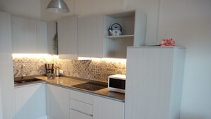A compact kitchen with white cabinets, a microwave, a kettle, and a sink. - Casa Maffei PLUS apartment 4, 1st floor, balcony, wonderful lake view, parking (Tignale)