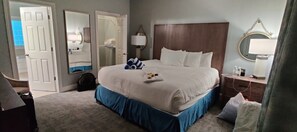 Relax in a spacious room with a large bed, a comfortable nightstand, and a mirror.