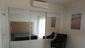 A bedroom with a bed, a chair, a wardrobe, and a wall-mounted air conditioner. - Superb apartment with port and sea view, large balcony, quiet, free parking, wifi (bandol)