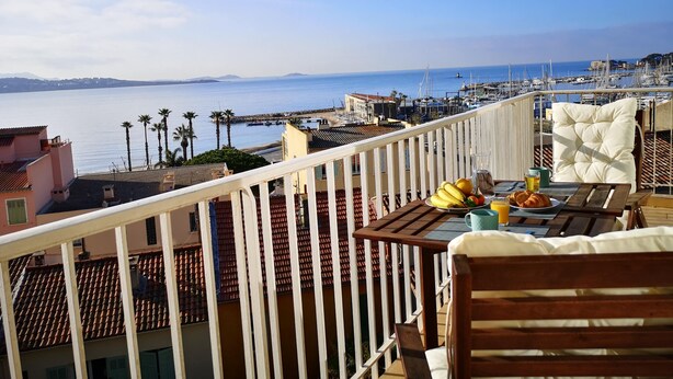 A balcony with a table set for breakfast, overlooking a marina and the sea. - Superb apartment with port and sea view, large balcony, quiet, free parking, wifi (bandol)