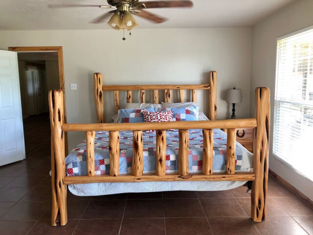 A wooden bed with a quilt, a ceiling fan, and a window with blinds.