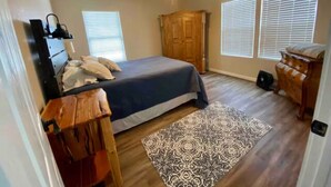 Ein Schlafzimmer mit einem Bett, einem Deckenventilator, einem Holzschrank und einem gemusterten Teppich.