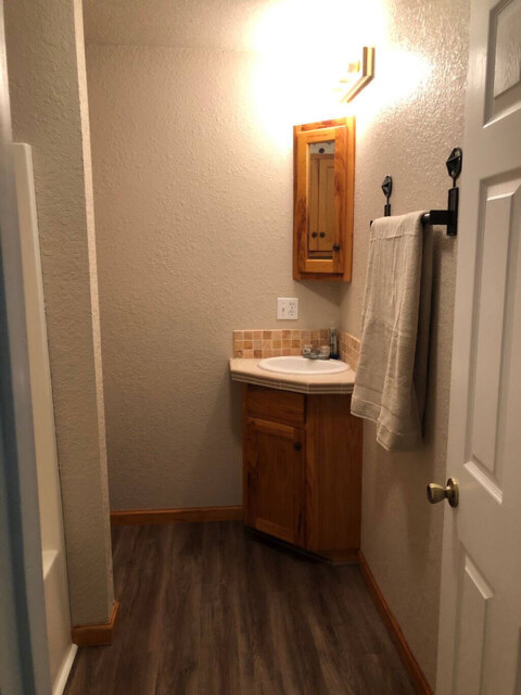 Une petite salle de bain avec un meuble-lavabo en bois, un évier et un miroir.