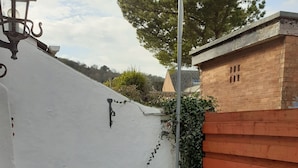 A rooftop terrace with a white wall, a wooden fence, and a metal railing. - House in Historic Village - Sleeps 6 (Minehead)