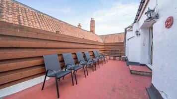 A red-tiled outdoor area with wooden benches and chairs.