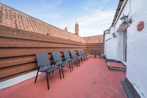 Un espacio al aire libre con tejas rojas, bancos y sillas de madera.