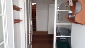 A narrow hallway with a brown carpet, white walls, and a wooden door on the left. - House in Historic Village - Sleeps 6 (Minehead)