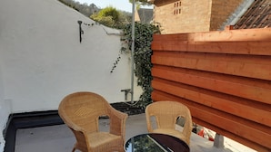 A small outdoor seating area with two wicker chairs and a round table. - House in Historic Village - Sleeps 6 (Minehead)