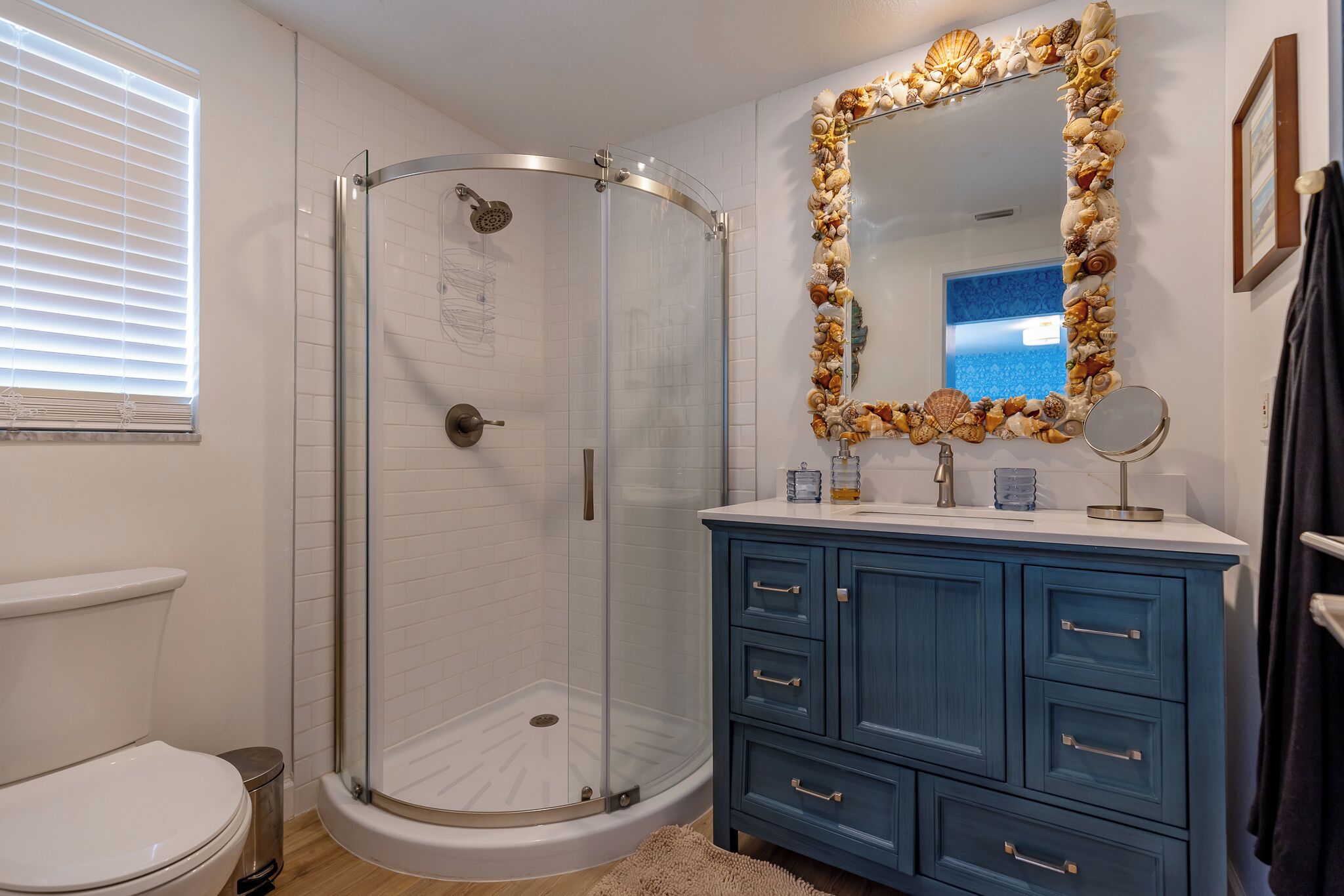 A bathroom with a glass-enclosed shower, a vanity with a mirror, and a toilet.