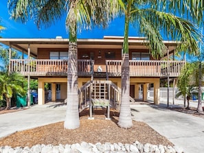 A two-story building with a balcony, palm trees, and a stone pathway. - Briney Breezes - Old Florida living with modern comforts (Anna Maria)