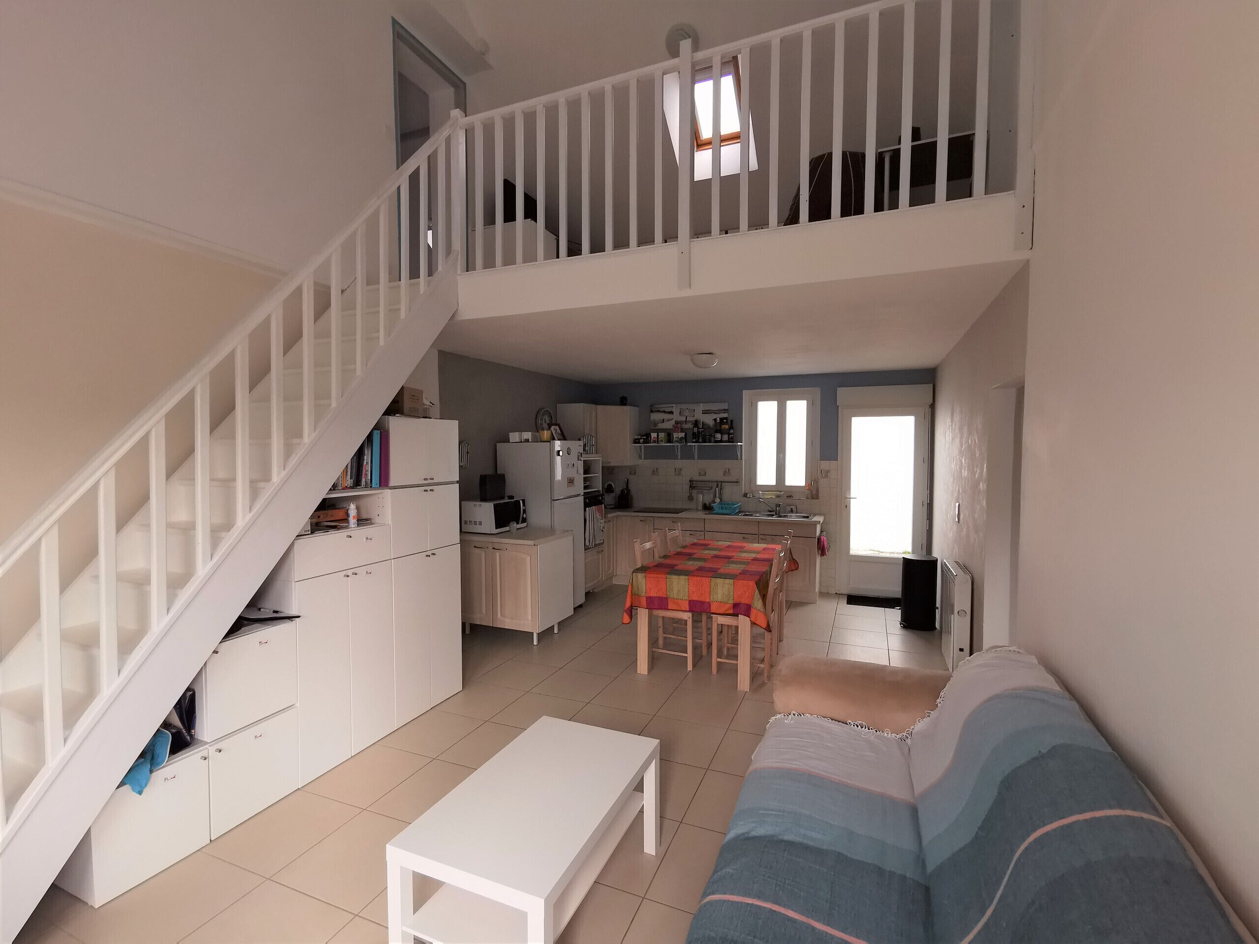 A spacious living area with a staircase, a kitchen, and a dining area.