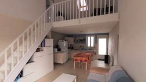 A spacious living area with a staircase, a kitchen, and a dining area.